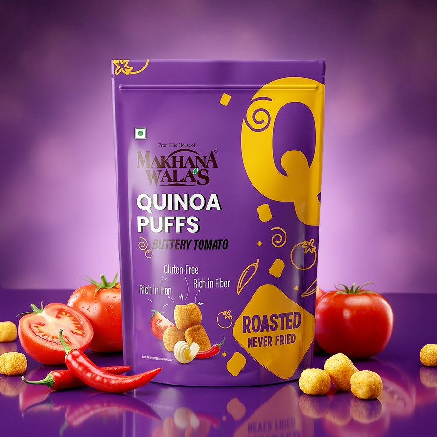 A bag of Makhana Wala's Quinoa Puffs in Buttery Tomato flavor, displayed on a purple reflective surface with tomatoes, red chilies, and loose puffs around it.
